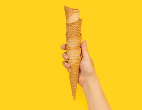 hand holding four ice cream cones on a yellow background